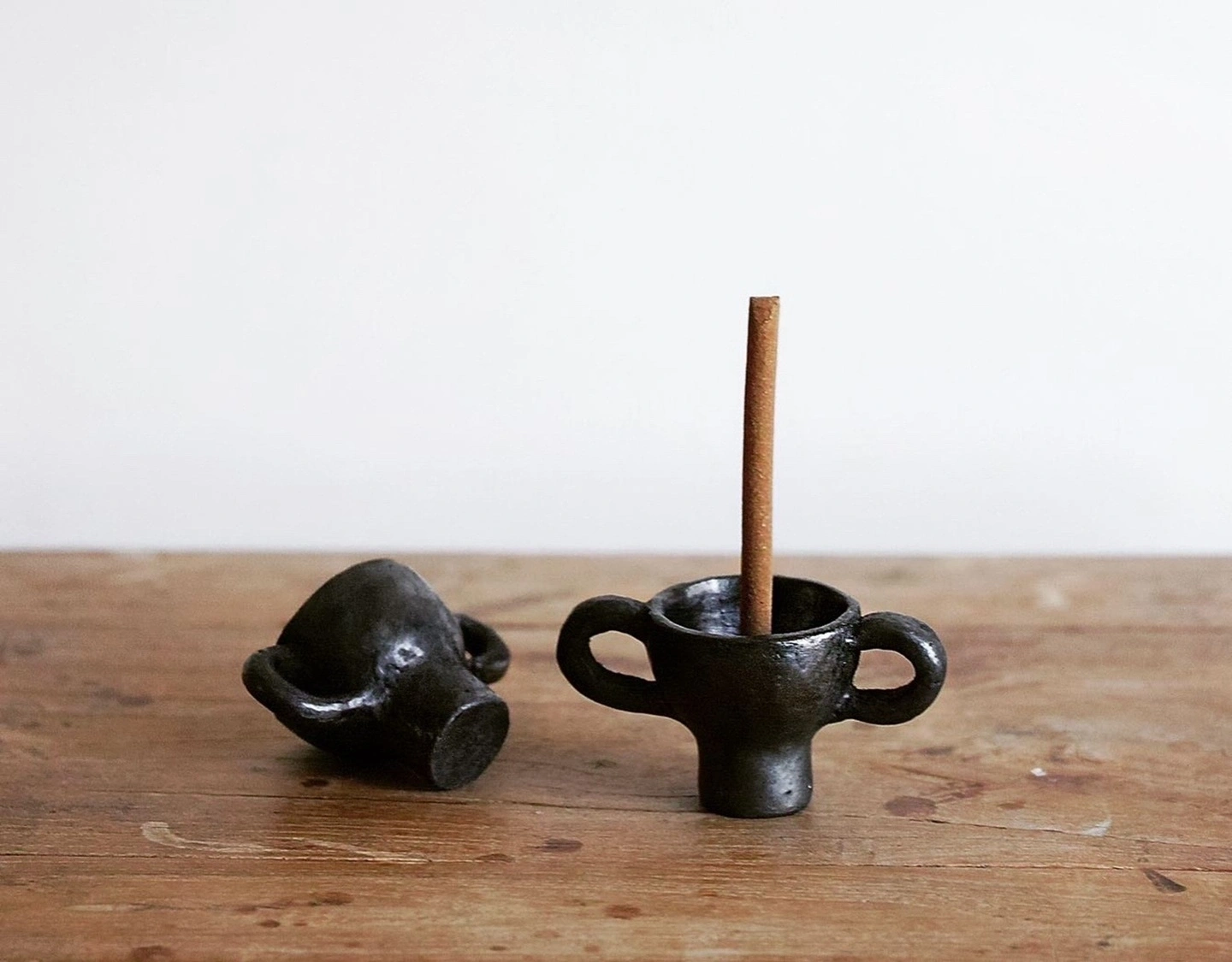 Two hand-pinched Tibetan black pottery dancing figurines on a rustic wooden table.