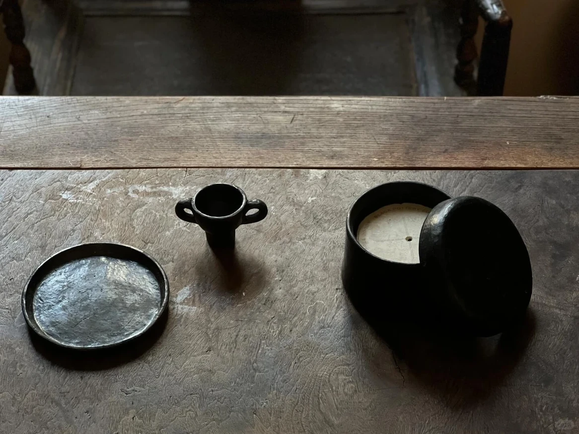 SUPERTIBET ensemble with black pottery plates, figurines, and Tibetan incense candles.