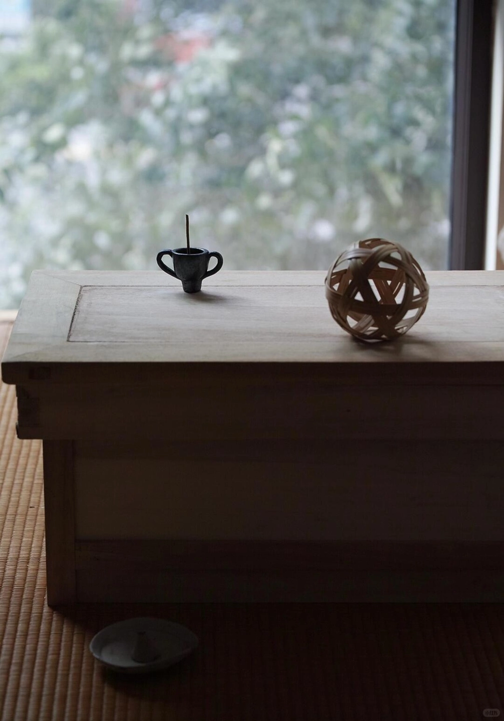 Zen lifestyle scene of a Tibetan black pottery incense burner on a wooden desk