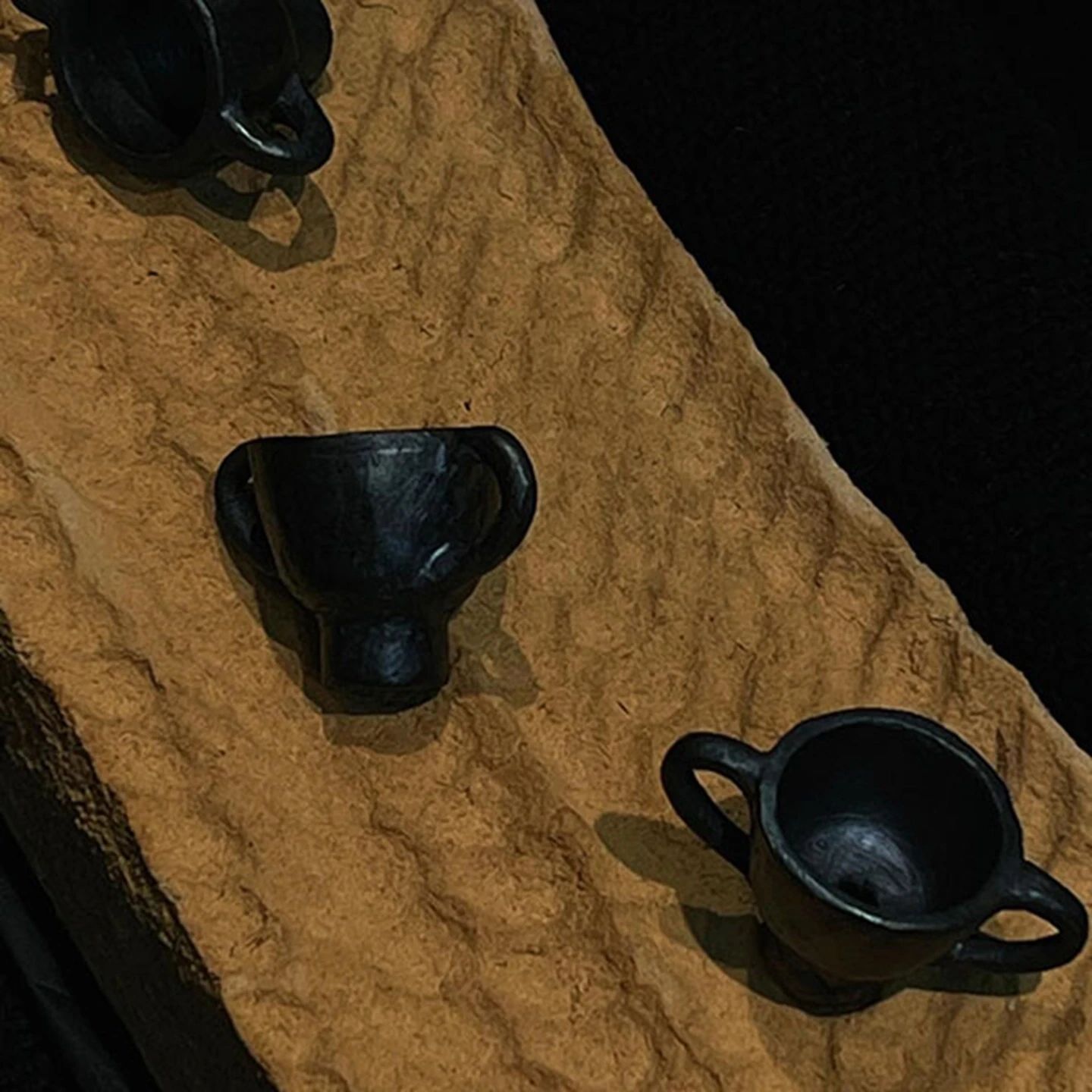 A collection of three handmade Tibetan black pottery dancing figurines in different poses.