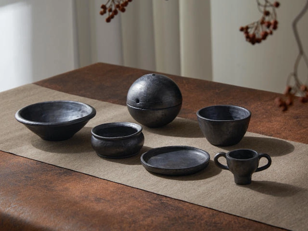 SUPERTIBET collection with black pottery incense holders, plates, and hand-pinched figurines.