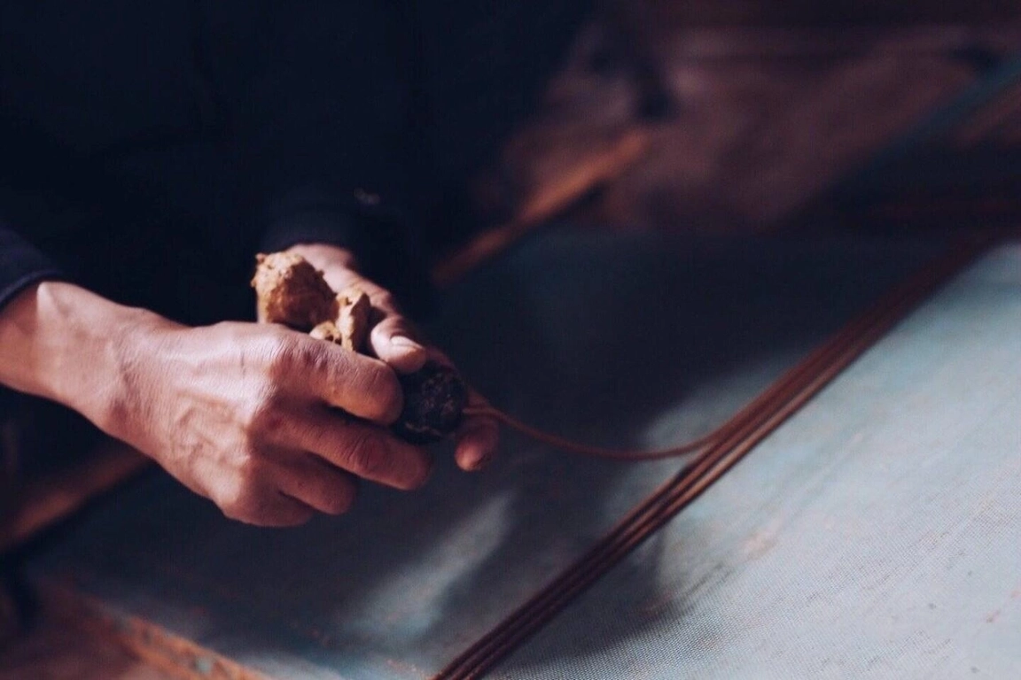 Traditional Tibetan incense shaping with a yak horn tool, pressing herbal paste into slender sticks.