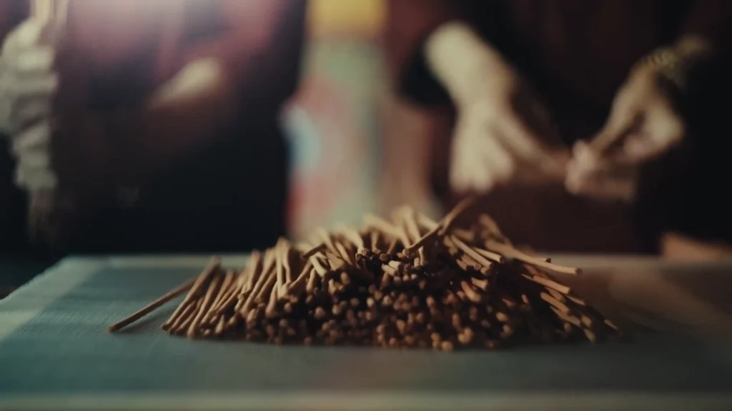 monks gather selected Tibetan incense sticks into small bundles on a worktable.